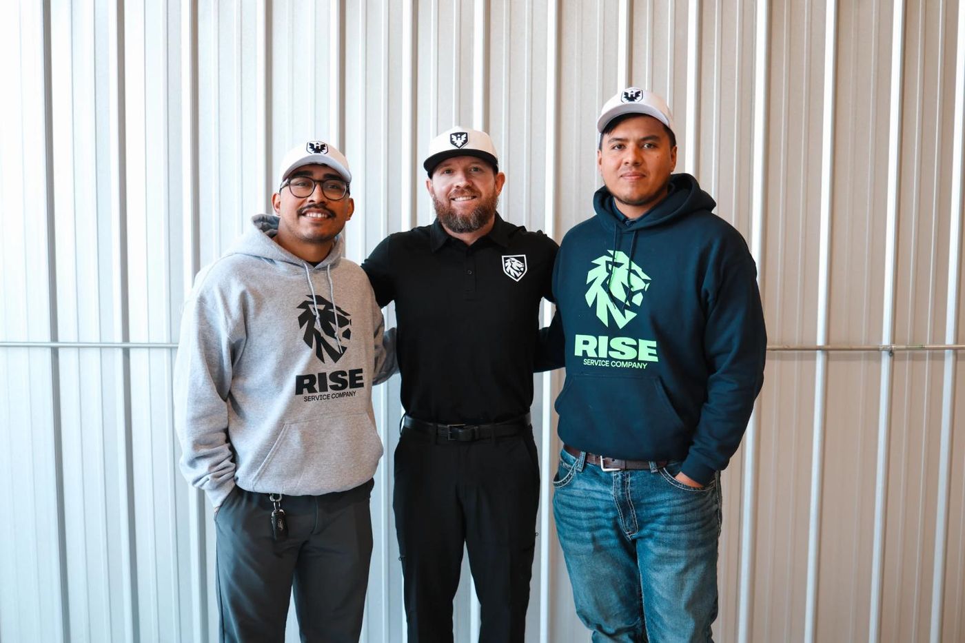Three Rise Service Company team members in Rise caps and hoodies